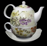 WINCY, Bule e xícara para chá empilhado com seu respectivo pires, porcelana esmaltada na tonalidade branca, decorados com flores e folhagens policromadas. Manufatura marcada no fundo. Medidas: 13x10cm / 13,5x12cm.