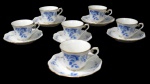 NORITAKE, Seis xícaras para café com seus respectivos pires, confeccionadas em porcelana esmaltada na tonalidade branca, arabescos realçados em relevo, pintura de flores e folhagens na tonalidade azul e bordas filetadas a ouro. Med.: 5x8,5x7cm / 12cm.