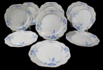 NORITAKE, Nove pratos rasos, confeccionadas em porcelana esmaltada na tonalidade branca, arabescos realçados em relevo, pintura de flores e folhagens na tonalidade azul e borda filetadas a ouro com pequenas falhas na douração. Med.: 27cm.