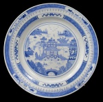 PORCELANA ORIENTAL, Medalhão em porcelana esmaltada na tonalidade branca, com pintura de elementos geométricos, folhagens, laços e paisagem oriental na tonalidade azul. Apresenta bicado na borda. Med.: 35cm.