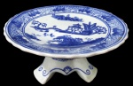 PORCELANA ORIENTAL, Fruteira de pé em porcelana esmaltada, com pintura de paisagens, elementos geométricos e folhagens na tonalidade azul, apoiado sobre 3 pés com decoração de arabescos. Med.: 10x20CM.