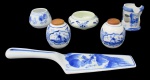 PORCELANA, Lote com 6 peças em porcelana esmaltada, sendo: A) DELF, 1 recipiente para molho em faiança vitrificada com pintura de flores e folhagens na tonalidade azul (4x9cm), B) Saleiro e pimenteiro em faiança vitrificada com pintura de flores, folhagens e fazenda na tonalidade azul, com tampa em madeira (7cm), C) 1 porta guardanapos em porcelana esmaltada na tonalidade branca, com pintura de flores e folhagens na tonalidade azul (6,5x5,5cm), D) 1 recipiente para mostarda em porcelana esmaltada na tonalidade branca com pintura de flores e folhagens na tonalidade azul e E) 1 pá de bolo em porcelana esmaltada na tonalidade branca com pintura de paisagem na tonalidade azul (24,5cm).