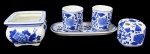 PORCELANA, Cinco peças em porcelana, sendo: A) 1 cachepot em porcelana esmaltada na tonalidade branca, com pintura de flores, folhagens e arabescos na tonalidade azul (9x12x12cm), B) 1 porta escovas em porcelana esmaltada na tonalidade branca com pintura de flores e folhagens na tonalidade azul, compartimento para 4 escovas (8x8x8cm), C) 1 bandeja oval em porcelana esmaltada na tonalidade branca com pintura de flores e folhagens na tonalidade azul (26x11cm) e D) 2 copos em porcelana esmaltada na tonalidade branca com pintura de flores e folhagens na tonalidade azul (9x7,5x7,5cm).