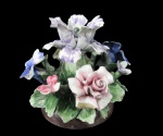 CAPODIMONTE, Itália, Arranjo de flores confeccionado em faiança italiana. Flores e folhagens ricamente modeladas e policromadas, base circular moldado com texturização simulando vaso Marca da manufatura ao fundo. Possui algumas flores com bicado e quebrado. Med.: 15cm.