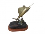 ESCULTURAS, Troféu de pesca em bronze representando Marlin, apoiado sobre base escalonada de madeira e mármore, placa com inscrições. Mármore rachado e nadadeiras quebradas. Med.: 27x23x18,5cm.