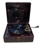 COLECIONISMO, Grafonola, marca Victrola - Victor Talking Machine Company / Camben N.J. - Caixa de metal revestida em couro, manivela a corda, braço quebrado, acompanha agulhas e 4 discos, Apresentas desgastes no couro. Peça no estado. Med.: 17x42x36,5cm.