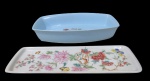 PORCELANA, Lote com 2 peças em porcelana, sendo: A) 1 travessa funda em porcelana refratária, esmaltada na tonalidade azul, com pintura de flores e folhagens em policromia (7x37x22,5cm) e B) 1 travessa para rocambole em porcelana esmaltada na tonalidade creme, com pintura de flores, folhagens e borboletas em policromia, assinado no verso (39,5x13,5cm).