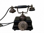 DIVERSOS, Antigo telefone de discagem, confeccionado em ferro esmaltado na cor preta, guarnições em metal dourado, pega em baquelite, falta bocal. Não testado e sem garantia de funcionamento. Med.: 23x25x18cm.