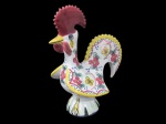 PORTUGAL, Galo de barcelos em faiança vitrificada, com pintura de flores e folhagens em policromia, assinado no verso. Med.: 21x15,5x11cm.