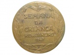 MEDALHAS, Medalha comemorativa confeccionada em bronze com inscrições: SEMANA DA CRIANÇA, RIO DE JANEIRO, 1947, verso: 1ª JORNADA BRASILEIRA DE PUERICULTURA E PEDIATRIA , com criança em relevo. Med.: 6cm.