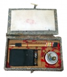 DIVERSOS, Estojo para caligrafia chinesa, composto de 2 pincéis em madeira, recipiente em porcelana com colher em metal dourado e 1 recipiente em grafite, acondicionado em estojo de madeira revestida em tecido (com desgastes). Med.: 3x17x10cm.