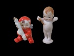 PORCELANA, Duas pequenas esculturas, sendo: A) 1 em biscuit representando criança (5cm) e B) 1 em porcelana esmaltada representando criança sentada segurando uma vela (4cm).