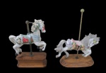 ESCULTURAS, Duas esculturas em biscuit, representando carrossel, ricamente decorado por flores e folhagens em relevo e policromia, sustentado por coluna em metal dourado, apoiado sobre base em madeira escalonada. 1 falta acabamentos para ficar fixa a coluna. Med.: 12x8,5x4cm / 14x11x5cm.