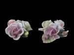 PORCELANA, Duas peças decorativas, confeccionadas em porcelana esmaltada, representando flores, decorada em relevo, pintura policromada, apresenta bicados. Med.: 3,5x6,5cm / 3x7x6,5cm.
