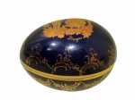 LIMOGES, França, Caixa porta joias no formato de ovo em fina porcelana esmaltada na tonalidade azul cobalto, ornada com cena galante em vasta douração. Borda filetada a ouro com pequenas falhas na douração. Marcada no fundo. Medidas: 6x8,5x6,5cm.