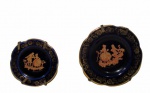 LIMOGES, França, Dois pequenos pratos decorativos em fina porcelana esmaltada na tonalidade azul cobalto, ornada com cena galante em vasta douração. Borda filetada a ouro. Med.: 8,5cm / 6,5cm.