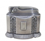 RONSON, DIANA, Isqueiro de mesa, confeccionado em prata de lei, cinzelado por gomos, folhagens e volutas, placa para monograma com incrições WCM. US PATENT RE. NO. 19023, D 154401, não testado e sem garantia de funcionamento. Med.: 6x7x3,5cm.