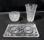 CRISTAIS, Lote com 3 peças em cristal translucido, sendo: A) 1 vaso com lapidação X em baixo relevo, formato sextavado com base cônica (13x8x8cm), B) 1 bandeja com lapidação de flores e folhagens em baixo relevo e borda dentada (19x11cm) e C) 1 bowl lapidado por losangos em baixo relevo, apresenta bicado na borda (6,5x8,5cm).