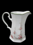 WINTERLING, ROSLAU, BAVARIA, RAPHAELA, Leiteira em porcelana esmaltada na tonalidade branca, formato oitavado, com pintura de flores e folhagens em policromia e bordas filetadas na cor verde. Med.: 19x18,5x10cm. Alça apresenta colado.