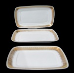 SCHMIDT, Três travessas retangulares em porcelana esmaltada na tonalidade branca, com pintura de flores e folhagens em espessa faixa em vasta douração, apresenta falhas na douração. Med.: 36x21cm / 33x18,5cm / 29x16cm.