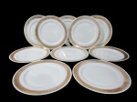 SCHMIDT, Dez pratos rasos em porcelana esmaltada na tonalidade branca, com pintura de flores e folhagens em espessa faixa em vasta douração, apresenta falhas na douração. 1 bicado. Med.: 26cm.