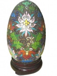 OBJETOS DECORATIVOS, Ovo confeccionado em cloisone, ricamente decorado por flores e folhagens em policromia, apoiado sobre peanha em madeira. Apresenta mossa no corpo. Med.: 16cm.