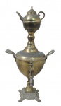 BRONZ, Samovar russo, confeccionado em bronze, cinzelado por motivos florais, alças laterais em forma de florão com vazado, apoiado sobre coluna cilíndrica, sustentado sobre quatro pés curvos, encimado por bule (possui mossa), possui sinais de oxidação. Med.: 40x21x20cm.