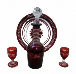 VIDROS, Lote com 4 peças em vidro pintado na tonalidade vinho, lapidado por uveiras e folhas de parreira em baixo relevo, sendo: A) 1 garrafa para licor (tampa adaptada) (20cm), B) 2 taças para licor (6x3cm) e C) 1 presentoir, apresenta bicados (19cm).