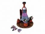 CENTRO ARTESAMAL, Higüerito, Moca, Republica Dominicana, Escultura confeccionada em barro vitrificado, representando figura feminina sentada com vasos de flores, ditas: "Muñeca sin rostro", esmaltada em rica policromia, apresenta flores quebradas. Med.: 21x18x17cm.
