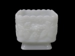 MILKGLASS, Vaso em vidro leitoso dito: Milkglass, formato quadrangular com rica decoração uveiras e folhas de parreira em relevo e bordas onduladas, apoiado sobre base quadrada escalonada. Med;: 10x11x11cm.