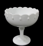 MILKGLASS, Fruteira de pé em vidro leitoso dito: Milkglass, corpo bojudo. com rica decoração pingos em relevo e bordas onduladas, coluna facetada, apoiada sobre base circular. Med.: 19x19cm.