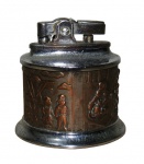 DIVERSOS, Isqueiro de mesa, confeccionado em metal prateado, centro em cobre, cinzelado por cenas distintas, apresenta sinais de oxidações, não testado e sem garantia de funcionamento. Med.: 6x6cm.