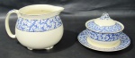 J&G MEAKIN, Inglaterra, Leiteira e açucareiro fixado a presentoir, confeccionados em faiança inglesa vitrificada, com pintura de motivos vegetalistas na tonalidade azul. Borda filetada a prata. Med.: 10,5x16x10cm / 8x10cm.
