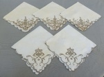 CAMA E MESA, lote com cinco (05) guardanapos da Ilha da Madeira confeccionados em linho na tonalidade bege com bordados floral em linha na cor castanho, sendo 3 com um bordado e 2 com outro diferente (um possui furos), medindo 44 x 43cm aproximadamente; usados.