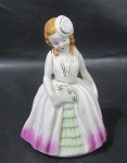 RAMI, Escultura em porcelana esmaltada na tonalidade branca representando dama antiga, pintura policromada e realces em ouro. Apresenta falhas na douração. Med.: 15cm.