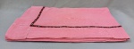 CAMA E MESA, lote com uma (01) toalha de mesa, confeccionada em linhão de algodão, na tonalidade rosa, com bordado desfiado, barrado com fita bordada, medindo aproximadamente 220x140 cm; usada, com manchas, remendos e bordado desfiado se desfazendo em alguns pontos.