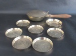 BRONZE - Oito peças em bronze polido com rico cinzelado de flores e folhagens, sendo: A) 1 cata migalhas com cabo em madeira (6x27x13cm) e B) 1 porta garrafas e 6 porta copos (9cm / 7,5cm).