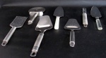 EQUIPAMENTOS PARA COZINHA, Lote com 7 peças em aço inox, sendo: 2 espátulas para bolo com cabos confeccionados em plástico rígido (25,5cm), 2 espátulas para cortar queijo (25cm / 23cm), 1 cortador de pizza (24,5cm), 1 abridor de coco (20,5cm) e 1 ralador (24,5cm).