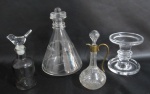 CRISTAIS/VIDRO - Lote com 3 garrafas e 1 castiçal, sendo: a) 1 pequeno licoreiro ricamente lapidado com sulcos e colmeias com alça e guarnições em metal dourado (17cm), b) 1 licoreiro em vidro fumê com lapidação de sulcos e colmeias com tampa translucida no feitio de pássaro (17cm), c) 1 garrafa com formato cônico em vidro translucido lapidada com motivos geométricos e tampa adaptada (22cm) e d) 1 castiçal em cristal translucido com haste escalonada (11x11cm).