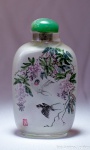 Snuf bottle em vidro com desenhos em bico de pena, assinado, tampa de jade, med. 8 x 4 cm. Estimativa R$ 350,00/ R$ 500,00