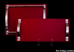 Duas bandejas retangulares em vidro vermelho, e detalhes de aço cromado, med. 20 x 45 cm e 30 x 40 cm. Estimativa R$ 180,00/ R$ 220,00