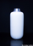 Moderna floreira cilindrica em porcelana no tom branco leitoso, borda em aço, assinada, alt. 32,5 cm.