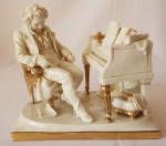 Fabuloso grupo escultórico de porcelana alemã, manufatura Scheibe-Alsbach, fundada em 1836. Representando Mozart compondo, em porcelana na cor pérola guarnecida em ouro. Peça numerada. Med. 19 x 20 x 14 cm. Estimativa R$ 800,00/ R$ 1.000,00
