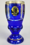 MOSER  IMPERIO AUSTRO HÚNGARO  GRANDE E PRECIOSO GOBLET EM CRISTAL AZUL E TRANSLÚCIDO DECORADO COM ROCAILLES EM OURO. REMATADO POR RESERVAS PASTILHADAS RELEVADAS E EMOLDURAS POR OURO COM ÓCULO CENTRAL APRESENTANDO  PAISAGENS AUSTRÍACAS. BASE DENTEADA. BOHEMIA, IMPERIO AUSTRIACO, SEGUNDA METADE DO SEC. XIX. 18 X 9 CM