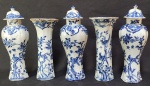 COMPANHIA DAS INDIAS REINADO QIANLONG  (1735-1796)  MAGISTRAL GARNITURE/GUARNIÇÃO EM PORCELANA DA COMPANHIA DAS INDIAS, REINADO QIANLONG COM DECORAÇÃO UNDERGLAZE AZUL. A EXUBERANTE DECORAÇÃO APRESNTA PÁSSAROS POUSADOS EM RAMOS DE  ÁRVORES FLORIDAS, RESERVAS COM CENAS  E ALDEIAS, RAMAGENS E FLORES. SÃO DOIS FLOREIROS E TRÊS POTES COM TAMPAS TOTALIZANDO CINCO PEÇAS. GARNITURES COMPLETAS COMO ESSA SÃO DIFICILMENTE ENCONTRADAS E ALTAMENTE COLECIONÁVEIS. VIDE NOS CRÉDITOS EXTRAS DESSE LOTE UM PROJETO DE DANIEL MAROT PARA UMA LAREIRA EXIBINDO DIVERSOS VASOS EM PORCENA CHINESA, AINDA ANTES DO ANO DE 1703. CHINA, CIRCA DE 1750. 25 CM DE ALTURA.NOTA:  As guarnições são conjuntos de vasos em porcelana com decoração a condizer, produzidos entre 1660 e 1830. Eram expostas como ornamentos, adornando ou 'enfeitando' uma cornija de lareira, mas também eram expostas acima de grandes armários e sobre portas. Às vezes também são chamados de garnitures de cheminée ('ornamentos para lareira'). A ideia de expor um vaso apenas para decoração remonta ao início de 1600, quando a porcelana chinesa começou a ser importada para a Europa. Vasos de cerâmica, lindamente pintados em azul sob o vidrado, foram adquiridos aos pares e como objetos únicos. Estes incluíam grandes potes de armazenamento com tampas combinando, copos cilíndricos altos e 'rolwagens' - um tipo de vaso com gargalo estreito. Na Holanda, onde a oferta era maior, eles eram mantidos acima de grandes armários em displays simétricos. O maior, geralmente um jarro, era posicionado no centro com béqueres nos cantos. Embora as cores combinassem, os designs não. Tais exibições são frequentemente registradas em pinturas e gravuras holandesas da década de 1650. As casas do século XVII eram muitas vezes escuras e mal iluminadas. Estas peças de porcelana brilhante, em branco puro e azul brilhante, proporcionavam floreios deslumbrantes em espaços escuros. Dispostos simetricamente acima de armários ou chaminés cobertas, eram símbolos de riqueza, privilégio e acesso a uma rede de comércio que se estendia por todo o mundo.A transição da dinastia Ming para a dinastia Qing na China foi tumultuada e, depois de 1647, as importações foram interrompidas. Como não havia porcelana nova disponível, os comerciantes franceses recorreram aos ceramistas holandeses em Delft, que conseguiram produzir cópias convincentes da porcelana chinesa, tanto em termos de forma como de decoração. Os consumidores ricos claramente queriam formas chinesas "tradicionais", incluindo Margaret Bankes, de Kingston Lacy, em Dorset, que comprou uma guarnição de três peças Delft no "estilo chinês" em 1698. Na década de 1650, a procura por guarnições disparou graças às mudanças no design de interiores. Com a introdução de lareiras mais proeminentes proporcionaram um ponto focal para pequenos produtos de luxo. Na França, os ceramistas começaram a fazer conjuntos de vasos em números ímpares de três, cinco, sete, nove e até onze para expor acima das lareiras. O termo francês 'garniture de cheminée' apareceu pela primeira vez no início da década de 1680, descrevendo um conjunto de sete vasos, bem como mais de 100 objetos de porcelana dispostos acima de uma lareira. Possuir porcelana chinesa era de fato o símbolo de um elevado status social e de bom gosto.  Petronella de la Court, esposa de um rico comerciante de Amsterdã, possuía, por exemplo, uma coleção de nada menos que 1.800 objetos de porcelana que eram exibidos com o maior cuidado por toda a sua casa.  Para expor esses objetos preciosos, os chamados porceleinkasten (vitrines) foram criadas a partir de 1700. Pode-se imaginar a impressionante impressão que esses belos armários cheios de luxo teriam dado aos visitantes da casa.