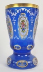 IMPÉRIO AUSTRO HÚNGARO  REQUINTADO GOBLET EM CRISTAL AZUL E LEITOSO DECORADO COM RESERVAS EM BAIXO RELEVO DECORADO COM RICOS ESMALTES FLORAIS E ARREMATES EM OURO. BORDA COM LARGO BARRADO EM OURO. ASSINADO COM MONOGRAMAEM OURO SOB A BASE. IMPÉRIO AUSTRO HÚNGARO, SEC. XIX. 15 CM DE ALTURA