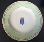 BARÃO DO RIO BRANCO (1845-1912) - JOSÉ MARIA DA SILVA PARANHOS. PRATO COVO EM PORCELANA, ABA AZUL ÁGUA DELIMITADA POR FRISO E FILETES DOURADOS, NO CENTRO DA CALDEIRA BRASÃO EM SUAS CORES HERÁLDICAS SOB COROA DE CONDE, PERTENCENTE A JOSÉ MARIA DA SILVA PARANHOS. NO REVERSO MARCA BOURGEOIS; REPRODUZIDO À PÁGINA 313 DO LIVRO LOUÇA DA ARISTOCRACIA NO BRASIL" POR JENNY DREYFUS. FRANÇA, SÉC. XIX. 23,7 CM DE DIÂMETRO.NOTA: José Maria da Silva Paranhos Júnior, nasceu em 20.04.1845, no Rio de Janeiro e era filho do diplomata e político José Maria da Silva Paranhos, o visconde de Rio Branco. A casa de seus pais era ponto de encontro de políticos da época. Assim, desde a infância, o futuro barão de Rio Branco foi aprendendo a diplomacia na prática. Durante a Guerra do Paraguai, viajou em 1869, junto com o pai, como secretário da Missão Especial ao Paraguai e à Argentina. Nos dois anos posteriores foi testemunha das negociações que puseram fim ao conflito entre os Aliados e o Paraguai. Estudou Direito nas Faculdades de São Paulo e do Recife. Seria promotor e deputado no Império. Igualmente foi jornalista escrevendo para o jornal A Nação e posteriormente, para o Jornal do Brasil. Como naquela época não havia concurso público para a diplomacia, os funcionários eram indicados entre os filhos da elite. Por isso, o barão do Rio Branco seguiu os passos do pai. Recebeu seu primeiro cargo diplomático no exterior devido ao relacionamento que mantinha com uma atriz belga, considerado um escândalo na época. Desta maneira é designado cônsul do Brasil em Liverpool. O barão do Rio Branco ainda seria ministro do Brasil junto à Alemanha. Voltaria ao Brasil a pedido do presidente Rodrigues Alves, para assumir a pasta do Ministério de Relações Exteriores. Ficou neste cargo de 1902 até a sua morte em 1912. O barão do Rio Branco defendia o uso da diplomacia e não da guerra para resolver os litígios de fronteira entre o Brasil e seus vizinhos. Foi o primeiro litígio resolvido com a ajuda do barão do Rio Branco. Brasil e Argentina disputavam territórios a oeste de Santa Catarina e a questão foi submetida à arbitragem internacional. O árbitro escolhido foi o presidente americano Grover Cleveland. Rio Branco foi designado para ser o advogado do Brasil na questão por Floriano Peixoto em 1893. Apoiado em farta documentação e mapas, o barão do Rio Branco, provou que aquelas terras eram brasileiras e deviam ser incorporadas ao Brasil e não à Argentina. As fronteiras do norte do Brasil também ainda não estavam definidas. Brasil e França alegavam que possuíam direito sobre parte do território do atual estado do Amapá. O atual estado do Acre era reivindicado por Brasil e Bolívia. Vários brasileiros estavam na região trabalhando nos seringais quando a Bolívia arrenda as terras a uma companhia americana. Diante das insurreições e revoltas, o governo brasileiro decide intervir. O barão do Rio Branco alega o princípio do uti possidetis que define que o território é de quem o ocupava. A solução do litígio teve fim em 1903 com o Tratado de Petrópolis. Este acordo cedia territórios do estado do Mato Grosso à Bolívia, pagamento de indenização e ainda construção da ferrovia Madeira-Mamoré. O título de "barão do Rio Branco" foi concedido ao diplomata pela Princesa D. Isabel, em 20.05.1888. Ele o usaria por toda sua vida, mesmo durante a República. Quando morreu, em 10.02.1912, em pleno Carnaval, a festa no Rio de Janeiro foi adiada por conta das homenagens e da comoção popular. Também em 1912, a capital do estado do Acre, então chamada Vila Pennápolis, passou a denominada "Rio Branco". Seu rosto estampou a antiga nota de 1000 cruzeiros durante anos. Por antonomásia, as pessoas passaram a designar "dinheiro" por "barão.