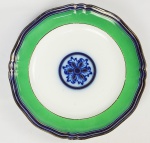 MARQUESA DE SANTOS. DOMITILA DE CASTRO CANTO E MELO (SÃO PAULO, 1797 - 1867). RARO PRATO RASO DE LOUÇA INGLESA NA COR VERDE DELIMITADO POR FRISO AZUL COBALTO COM FILETES DOURADOS EM RELEVO. OSTENTA AO CENTRO DA CALDEIRA ROSETA EM AZUL COBALTO COM DETALHES EM DOURADO. EXEMPLAR DO SERVIÇO ESTÁ REPRODUZIDO À PÁGINA 523 DO LIVRO "O BRASIL E A CERÂMICA ANTIGA", DE ELDINO DA FONSECA BRANCANTE. CARMO CHAGAS EM SUA OBRA  OS OLIVEIRA COSTA DE TAUBATÉ RELATA QUE AMADOR RODRIGUES LACERDA JORDÃO, O BARÃO DE SÃO JOÃO DO RIO CLARO (1825-1873), DONA DA FAZENDA SANTA GERTRUDES E FILHO DO BRIGADEIRO JORDÃO, QUANDO ESTEVE NO COMANDO DA TROPA DE SÃO PAULO  ORDENOU  QUE A BANDA DO PALÁCIO, SITUADO NO PÁTIO DO COLÉGIO, TOCASSE UM DOBRADO TODA VEZ QUE A MARQUESA D ESANTOS ADENTRASSE A PRAÇA, DEFERÊNCIA MUITO APRECIADA POR ELA.  INGLATERRA, SÉCULO XVIII/XIX. 26 CM DIAMETRO. NOTA: Referência a esse serviço é apresentada no livro "A Marquesa de Santos" de Paulo Setubal: este serviço, apesar de não ser personalizado, aparece nitidamente descrito em documentos na época do casamento da jovem Domitila de Castro no alvorecer do século XIX. "Era um destramelar de armários, um remexer em empoeiradas arcas, um revirar canastras, um escancarar baús, um arrancar lá do fundo de tudo isso para expor ao sol, os preciosos guardados antigos, as coisas nobres e magníficas, as toalhas de crivo, as rendas de bilros, os panos bordados, a prataria do Reino, as peças de Porcelana. Sobretudo com muitos mimos era um esfregar aquelas pesadas louças de friso azul tão faladas na cidade".