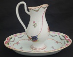 COMPANHIA DAS INDIAS- REINADO JIAQING (1796-1820)  - FORMIDÁVEL GOMIL E LAVANDA EM PORCELANA CHINESA DO PERÍODO JIAQING. DECORADA COM ESMALTES EM ROSA, AZUIS, VERDES  E ROUGE DE FEUR. A BORDA DA LAVANDA TEM FILETE EM OURO E REQUINTADA DECORAÇÃO SIMULANDO LONGAS PLUMAS COLORIDAS REALÇADAS TAMBÉM EM OURO. SUCEDENDO A BORDA, UMA GUIRLANDA COM FLORES FORMANDO FESTÕES. A CALDEIRA É REMATADA POR ESMALTES FLORAIS REMETENDO A FAMILIA ROSA EMOLDURADOS POR CORDÉU EM CORAL. O GRACIOSO GOMIL SEGUE O MESMO PADRÃO DECORATIVO E A ALÇA TEM EM RELEVO LINDAS FOLHAS EM AZUL E OURO. BELISSIMA PRODUÇÃO DO FINAL DO SEC. XVII ONDE SE PERCEBE A TRANSIÇÃO DA INFLUENCIA QIANLONG PARA O JIAQING. CHINA, FINAL DO SEC. XVIII. 33 CM DE COMPRIMENTO (LAVANDA))NOTA: Há 800 anos Marco Polo, trouxe da China para o ocidente uma das primeiras peças em porcelana, um pequeno jarro verde acinzentado que está até hoje no tesouro da Basílica de São Marco em Veneza. Essa foi a semente da obsessão da Europa pelo Ouro Branco. No crepúsculo da DINASTIA MING, chegou à China em 1698 o Padre Jesuíta François Xavier d'Entrecolles. O declínio Ming sobreveio de uma crise causada pela corrupção, a exploração da classe dominante e desastres naturais durante anos sucessivos. Os rebeldes começaram a tomar o poder em algumas regiões e a dinastia chegou ao seu oficial fim com o suicídio do último imperador, Weizong. O poder passou então a nascente Dinastia Qing, que por 250 anos governou a China e sobre seu domínio a produção da porcelana Companhia das Indias atingiu seu apogeu em beleza e volume. Estima-se que 60 milhões de peças de porcelana foram exportadas para Europa nesse período. O Imperador QIANLONG governou o país por quase todo o sec. XVIII. Pouco antes do inicio desse grande reinado, ainda sob o período KANGSHI chegou a China o Padre DEntrecolles. Veio para salvar almas dos pagãos mas teve a sua própria alma arrebatada pela obsessão da porcelana. O ouro branco, encantou os europeus desde o primeiro leilão fruto da carga apreendida pelos holandeses de dois navios Portuguses. Era tão alto o preço da porcelana da China que um aparelho de jantar custava o equivalente ao valor de um pequeno palácio. Foi então que na Europa começou a busca da fórmula da composição e do processo para fabricação da porcelana. A princípio, julgaram que era feita a partir de conchas e casca de ovos moídos e tentaram reproduzir o efeito com esses matérias. Claro, tudo em vão porque a porcelana nada tinha a ver com esses elementos. O primeiro Imperador da Dinastia Qing foi Kangxi e este deu ordens de esconder, sob pena de morte, o processo de fabricação. O Padre DEntrecolles valeu-se dos chineses convertidos de Jingdezhen para descobrir aos poucos o processo. Um dia finalmente ele descobriu o segredo mais importante para obtenção da porcelana, em uma região remota chamada KAO-LING (COLINA ELEVADA) os chineses extraiam há séculos a argila chamada caulim que era o principal elemento constituinte da louça da China. O resto, as proporções, o modo de fazer, de decorar e a queima ele cuidou em aprender gradativamente. Em 1712 o Padre DEntrecolles escreveu para França relatando suas descobertas e descrevendo em minúcias o processo de fabricação. Dessa forma um segredo milenar foi revelado a Europa ensandecida pela porcelana e sua capacidade de trazer riquezas além de qualquer sonho aos homens. Paralelamente na Europa, Augusto II, chamado O FORTE, aprisionou em seu castelo um jovem aprendiz chamado BOTTEGER, que se gabava de ser alquimista, e o ameaçou de pena de morte se não conseguisse desvendar o processo para a fabricação. Cinco anos BOTTEGER esteve preso realizando experimentos sistemáticos até chegar por seu próprio mérito à fórmula da porcelana. Embora não tenha sido um método muito ortodoxo, funcionou. Surgiu a manufatura de Meissen. Nessa mesma época na China, LANG TINGJI, foi nomeado pelo Imperador KANGXI, supervisor de porcelana nos fornos de Jingdezhen. A intenção do Imperador era a de recriar as famosas porcelanas monocromáticas do período Ming do SEC. XIV. Os chineses tem essa particularidade, um respeitoso culto aos ancestrais e suas conquistas. Edmund de Waal em seu livro O Caminho da Porcelana: A jornada de Uma Obsessão (recomendo muitíssimo) referencia assim essa respeitosa paixão pela memória dos ancestrais: Esse pode ser o ano em que alguém encomenda a fabricação de turíbulos que se parecem muito com os turíbulos feitos há trezentos anos. Esses por sua vez foram feitos para aludir bronzes de 900 anos atrás. Assim a devoção atravessa os séculos e as gerações. LANG TINGJI era extremamente dedicado e mergulhou fundo na tarefa que lhe foi destinada. O problema é que o pigmento de vermelho intenso que dá o tradicional aspecto vidrado dessas porcelanas conhecidas no mundo ocidental como sang de boeuf (sangue de boi) era feito a base de coral e ágata o que o tornava extremamente caro. O próprio fabrico era delicado, principalmente quanto ao processo de queima e a porcelana que LANG TINGJI finalmente conseguiu reproduzir, tinha uma margem de perda muito grande e passou a ser conhecida como 100 para 1 (a cada 100 peças somente uma era aproveitada). Mas esse custo não desmotivou o imperador KANGXI afinal ele era o grande imperador iniciador da dinastia QING. Ele era um homem 100 para 1. Tamanho era esse custo de produção que gerou um ditado sobre a porcelana de LANG como ficou então conhecida, em homenagem a seu redescobridor: Quer ficar pobre? Faça porcelana de Lang. Hoje nós conhecemos essa produção como LANG YAO. DEntrecolles, Botteger e Lang, três homens trabalhando separadamente e com perseverança, sem se conhecer, com motivações e objetivos distintos, mudaram a história do mundo. A porcelana chinesa antiga ainda traz encantamento por sua beleza, sua coloração branca azulada e a magnífica decoração. Não por acaso, cada peça de porcelana Companhia das Índias que nos chega à mão é tratada com reverência e devoção não apenas por ser fruto do trabalho do oleiro que lhe deu forma e a decorou, mas por ser produto de 5000 anos de uma cultura extraordinária e única.