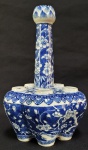 COMPANHIA DAS INDIAS  REINADO DAOQUANG (1820-1850)  VASO PARA TULIPAS  RARO VASO PARA TULIPAS EM PORCELANA DECORADA EM AZUL UNDERGLAZE COM FLORES DE AMEIXEIRA E SUAS RAMAGENS. DOTADO DE SEIS FUROS. O FURO CENTRAL QUE SE ELEVA SOBRE O GARGALO TEM FEITIO DE FLOR DE LOTUS. VASOS DE TULIPA FORAM PRODUZIDOS SOB ENCOMENDA DA COMPANHIA DAS INDIAS  NA CHINA PARA ATENDER O MERCADO HOLANDÊS NO AUGE DA TULIPAMANIA O PERÍODO EM QUE UM BULBO DE TULIPA PASSOU A VALER MAIS DO QUE UM DIAMANTE. ESSE PERÍODO NO SEC. XVII FICOU CONHECIDO COMO A PRIMEIRA GRANDE BOLHA ESPECULATIVA DA HISTÓRIA. SEJA COMO FOR, PARA OSTENTAR RIQUEZA E PROSPERIDADE ESSES VASOS DE TULIPA ERAM CENTROS DE MESA EM REQUINTADOS BANQUETES, CADA FURO DESTINAVA-SE A APENAS UMA EFÊMERA TULIPA. CHINA, PRIMEIRA METADE DO SEC. XIX. 31 CM DE ALTURANOTA: Um tipo completamente diferente de mania das tulipas atingiu seu auge no século XVII. A amada flor originou-se originalmente do Oriente e foi apenas por acidente que o bulbo chegou ao clima costeiro ocidental da Holanda.As tulipas já eram apreciadas há séculos no Império Otomano, bem como no que hoje são a Índia, o Paquistão e o Afeganistão, onde as flores decoravam jardins e palácios. Não foi por acaso que o nome deles é semelhante à palavra para turbante. No século 16, Ogier Ghiselin de Busbecq servia como embaixador da monarquia dos Habsburgos no Império Otomano. Ao visitar o sultão turco Suleiman, o Magnífico, um fã de tulipas, ele recebeu alguns bulbos para levar de volta a Viena. De Busbecq então passou os bulbos de tulipa para seu amigo, o botânico flamengo Charles de l'Écluse, prefeito do jardim do imperador em Viena. Quando d'Écluse deixou Viena para lecionar numa universidade em Leiden, na Holanda, ele trouxe os bulbos e os plantou lá. Como diretor do jardim botânico de Leiden, ele fez experiências com a flor exótica - e teve tanto sucesso que a tulipa se tornou uma importação muito procurada entre os residentes ricos locais. As flores foram especialmente procuradas devido à sua sensibilidade. O clima úmido e frio não atendia bem aos bulbos e eles eram suscetíveis a doenças. Um vírus específico foi transmitido através de pulgões de flor em flor  mas tornou as pétalas multicoloridas, resultando em flores especialmente exclusivas. Conhecidas como tulipas Rembrandt, a variedade colorida foi posteriormente cultivada artificialmente. A tulipa rapidamente se tornou um símbolo de status. À medida que as vendas comerciais se desenvolveram, os preços tornaram-se exorbitantes. Algumas pessoas até trocaram tudo o que possuíam para comprar um bulbo  sem saber se algum dia ele cresceria. Na época, a variedade mais cara era a Semper Augustus, e custava tanto quanto uma casa de canal em Amsterdã. As próximas colheitas foram especuladas e o mercado cresceu descontroladamente - até que, um dia, na primavera de 1637, o mercado de tulipas quebrou quando os preços caíram durante a noite. Muitas pessoas enriqueceram com a mania das tulipas, mas a maioria não previu o revés e perdeu tudo. As tulipas, no entanto, conseguiram salvar outras pessoas. Séculos mais tarde, no outono de 1944, os Aliados perderam a Batalha de Arnheim para os nazistas. Como resultado, grandes partes dos Países Baixos ficaram sem fornecimento de carvão e alimentos, uma vez que os alemães bloquearam as raízes de abastecimento. Naquele inverno, ocorreu uma fome conhecida em holandês como "Hongerwinter", ceifando até 22.000 vidas. Durante a Segunda Guerra Mundial, os produtores holandeses de tulipas não plantaram flores, armazenando seus muitos bulbos em locais secos. As autoridades decidiram distribuir os bolbos de tulipas como alimento e convenceram os produtores a vendê-los. Os bulbos mostraram-se nutritivos e fáceis de cozinhar. Embora provavelmente não tivessem um gosto muito bom, salvaram muitas vidas.